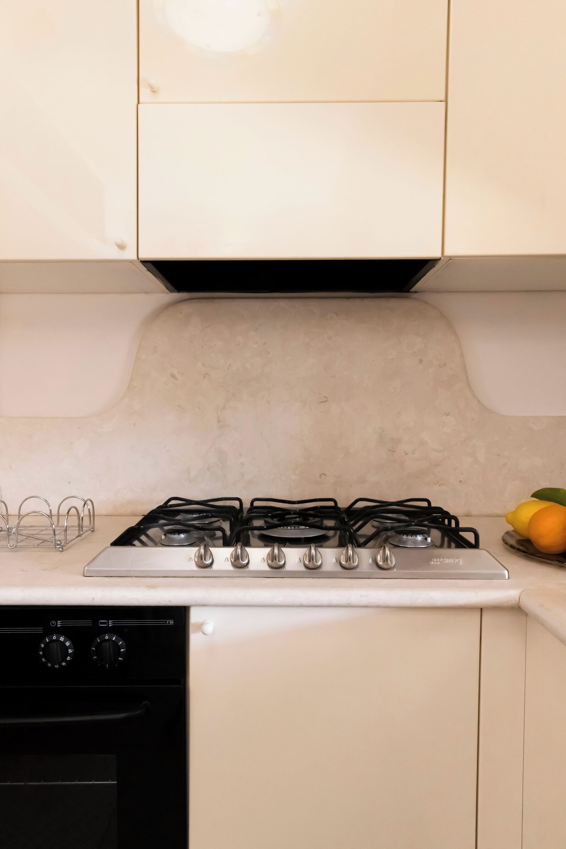 A kitchen with a white stove, black oven, and white cabinets.