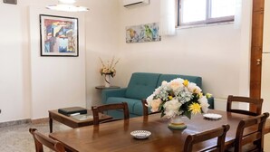 Un comedor con una mesa y sillas de madera, un jarrón de flores y obras de arte en las paredes.
