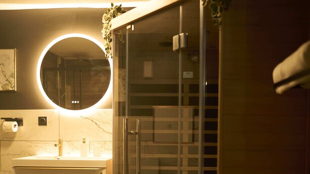 A modern bathroom with a glass shower enclosure, a round mirror, and a white vanity. - La Romance Room - Jacuzzi | Cinema | Sauna (Arnouville)