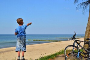 A child pointing towards the sea, a bicycle, and a tree. - Large holiday apartment (Kolobrzeg)