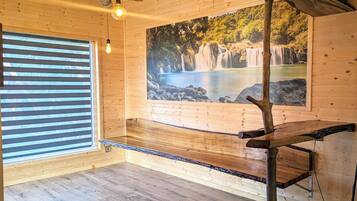 A wooden interior with a bench, a hanging light, and a waterfall mural.
