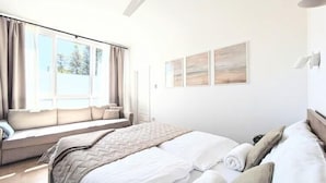 A bedroom with a bed, a window seat, and artwork on the wall. - Large holiday apartment with sauna (Kolobrzeg)