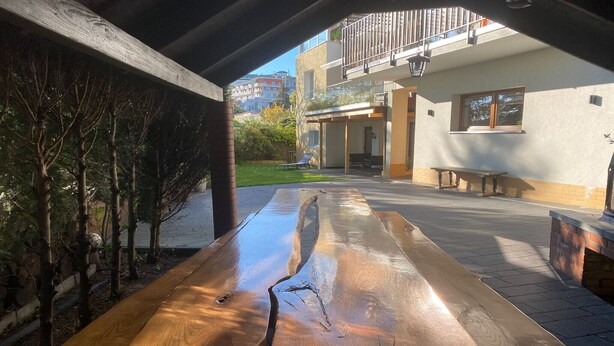 Una mesa de picnic de madera en un espacio exterior con vista a un edificio al fondo.