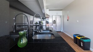 A modern kitchen with stainless steel appliances, a black countertop, and a green vase. - Great remodeled apartment - 5 min to the beach! (Carcavelos)