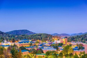 A town with a mix of modern and historic buildings, surrounded by hills and trees.