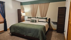 A bedroom with a bed, a nightstand, a lamp, and a wardrobe. - Mountain Views, Boone, Blowing Rock & Parkway (Boone)