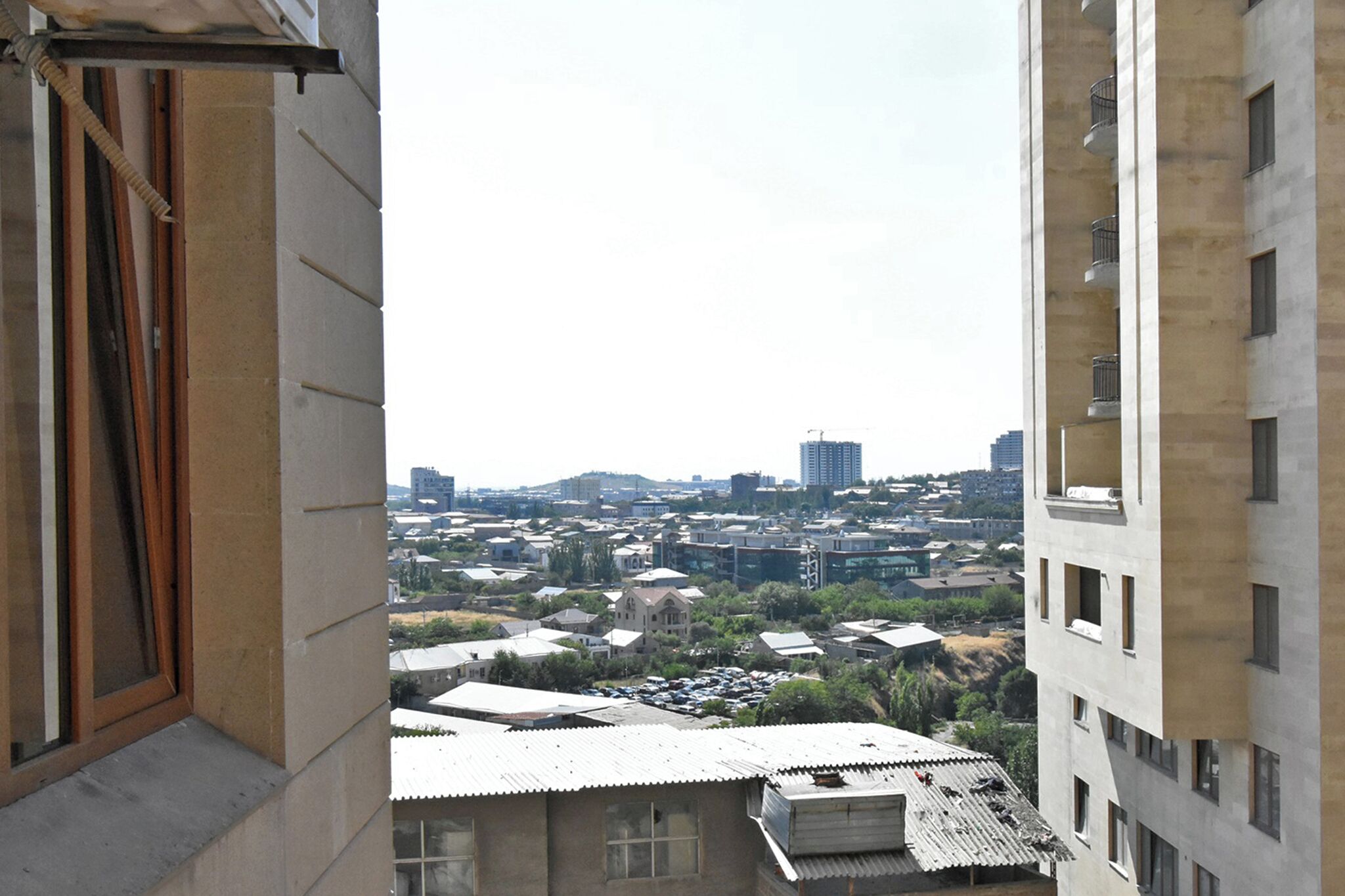 A view from a window overlooking a cityscape with various buildings, including a tall skyscraper in the distance.