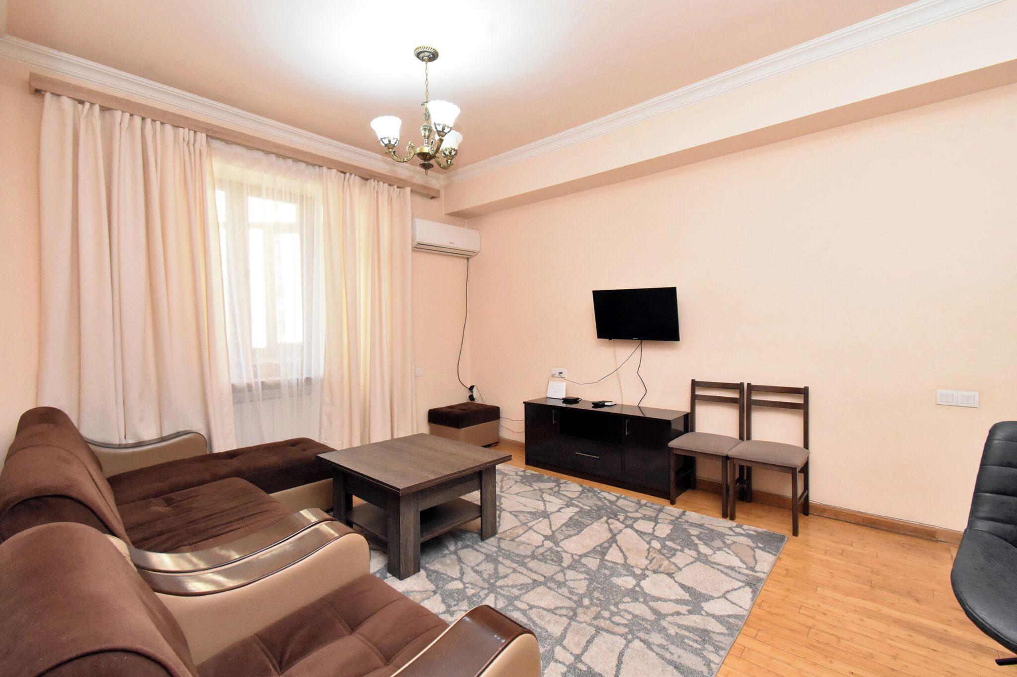 A living room with a sofa, a coffee table, a TV, and a small cabinet.