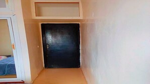 A narrow hallway with a black door at the end, a white wall, and a tiled floor. - Sweet sleep (Casablanca)