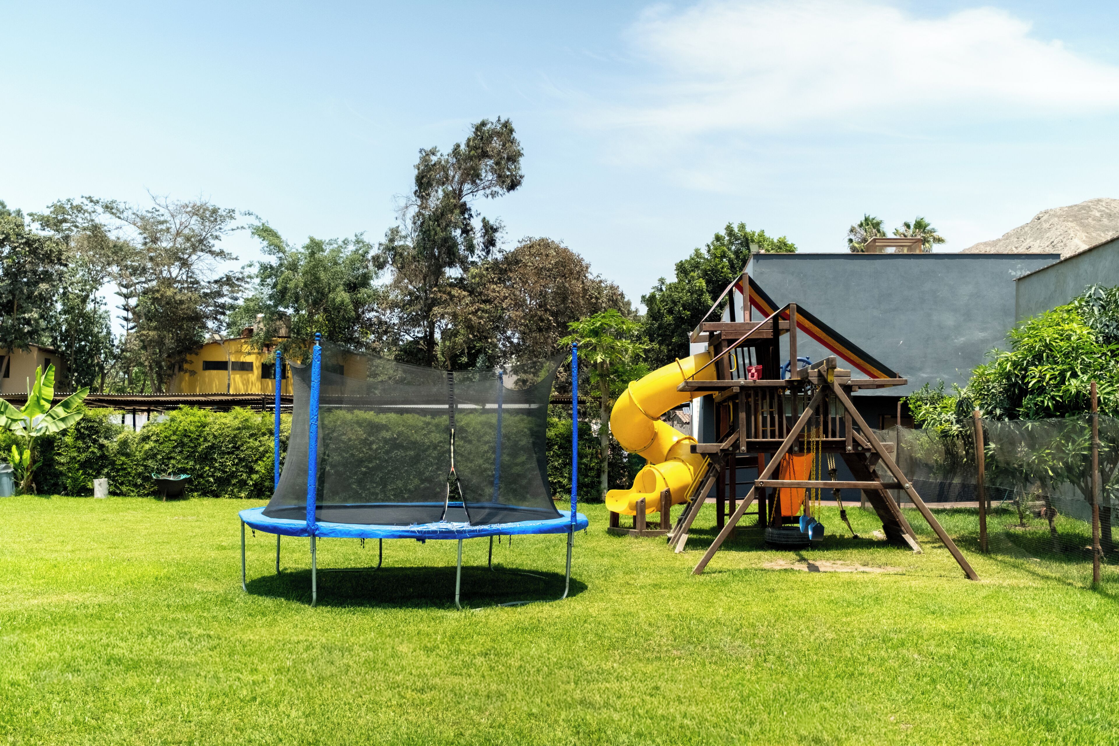 A playground with a trampoline and a yellow slide.
