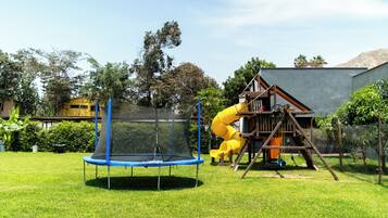 A playground with a trampoline and a yellow slide.