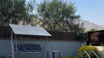 A swimming pool with a sunshade, a lounge chair, and a small table.