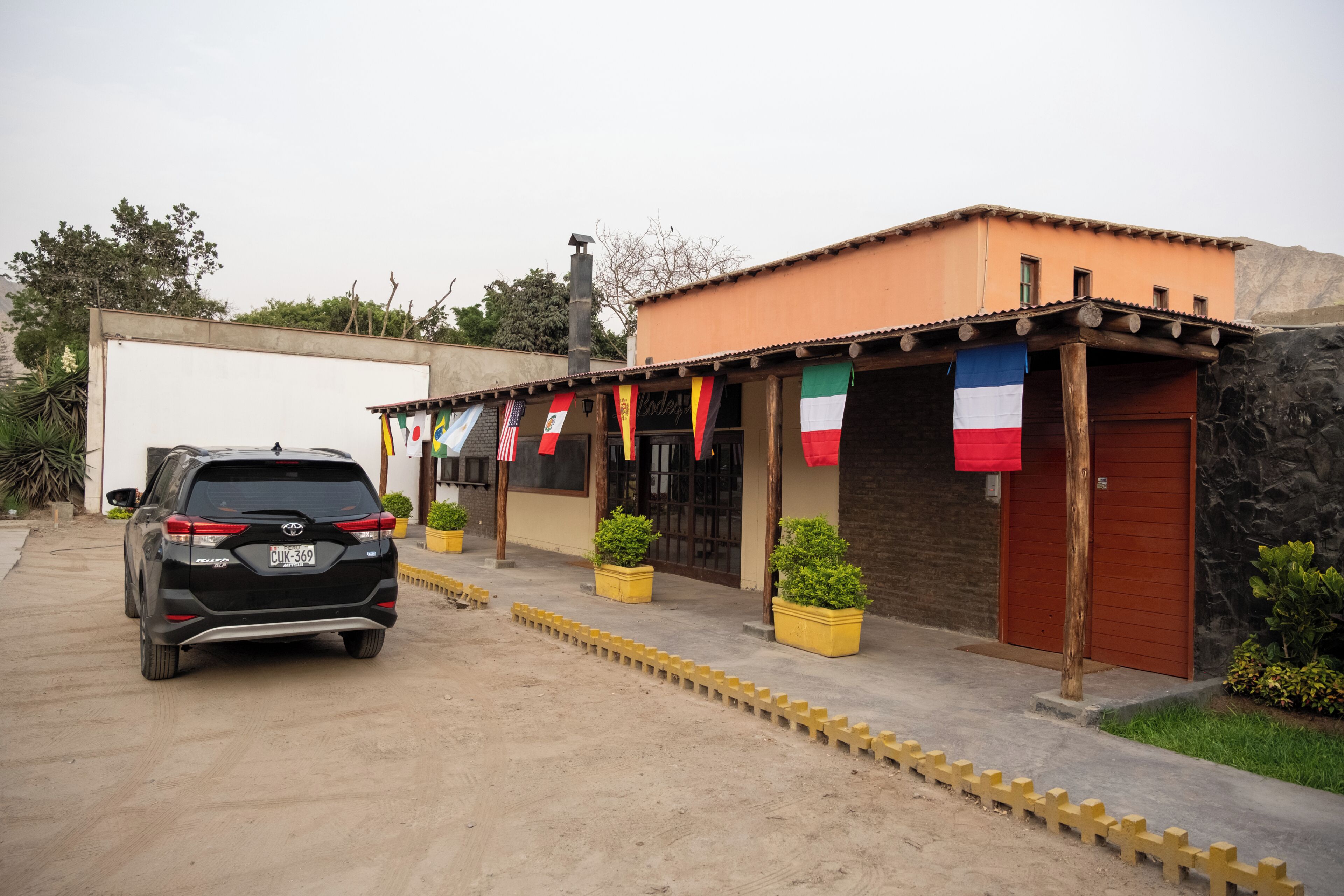 A building with a garage, potted plants, and a car parked in front.