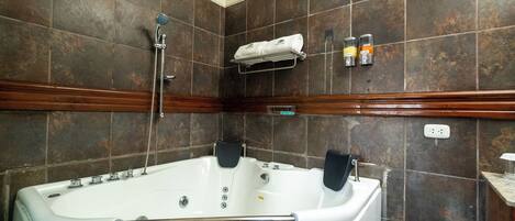 A bathroom with a large bathtub, a shower, and a towel rack.
