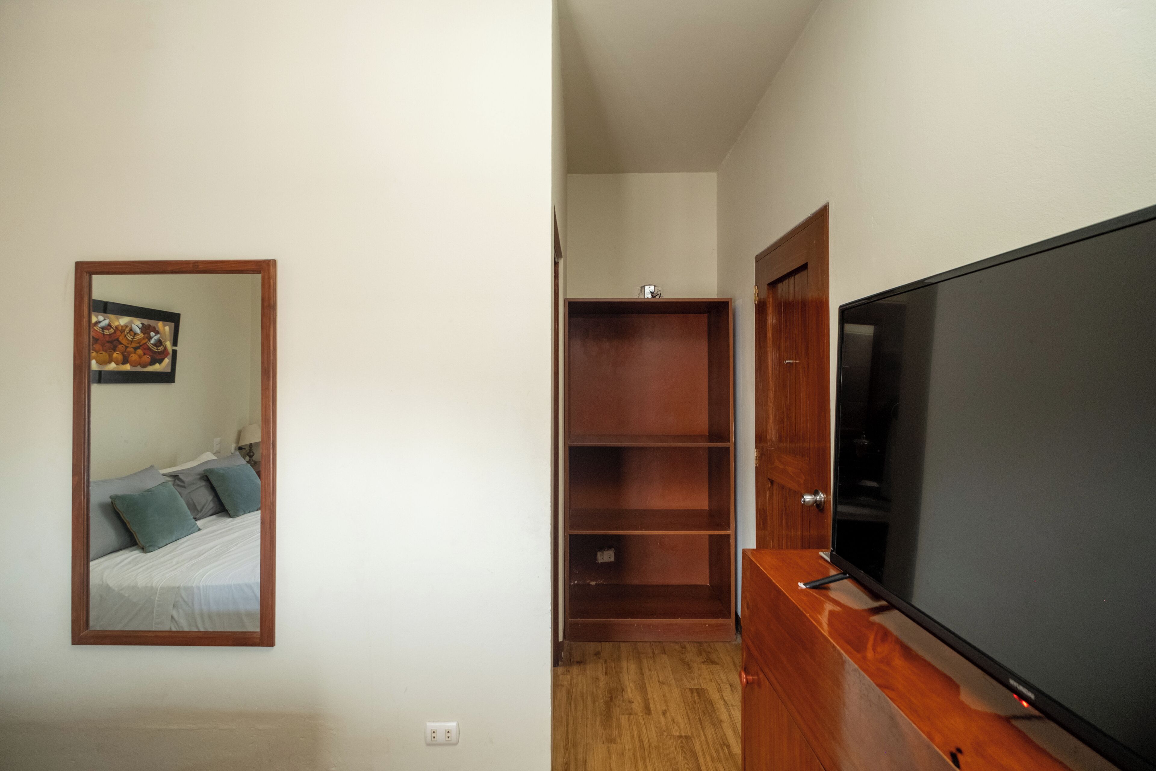 Un dormitorio con una cama, televisor y un armario de madera.