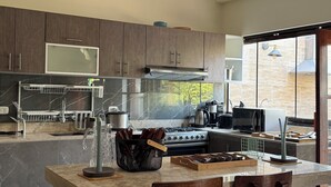 A modern kitchen with dark wooden cabinets, a marble backsplash, and a large island with bar stools. - Casa de Campo Bungalows & Suites (Cieneguilla)