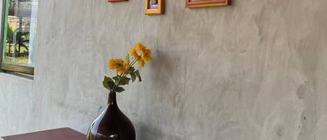 A wall with multiple framed artworks and a vase with flowers on a table.