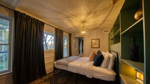 Une chambre avec un grand lit, un tapis à motifs, un lustre et une vue sur l’extérieur.