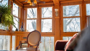 Une pièce chaleureuse avec de grandes fenêtres, un plafond en bois et un coin salon confortable.
