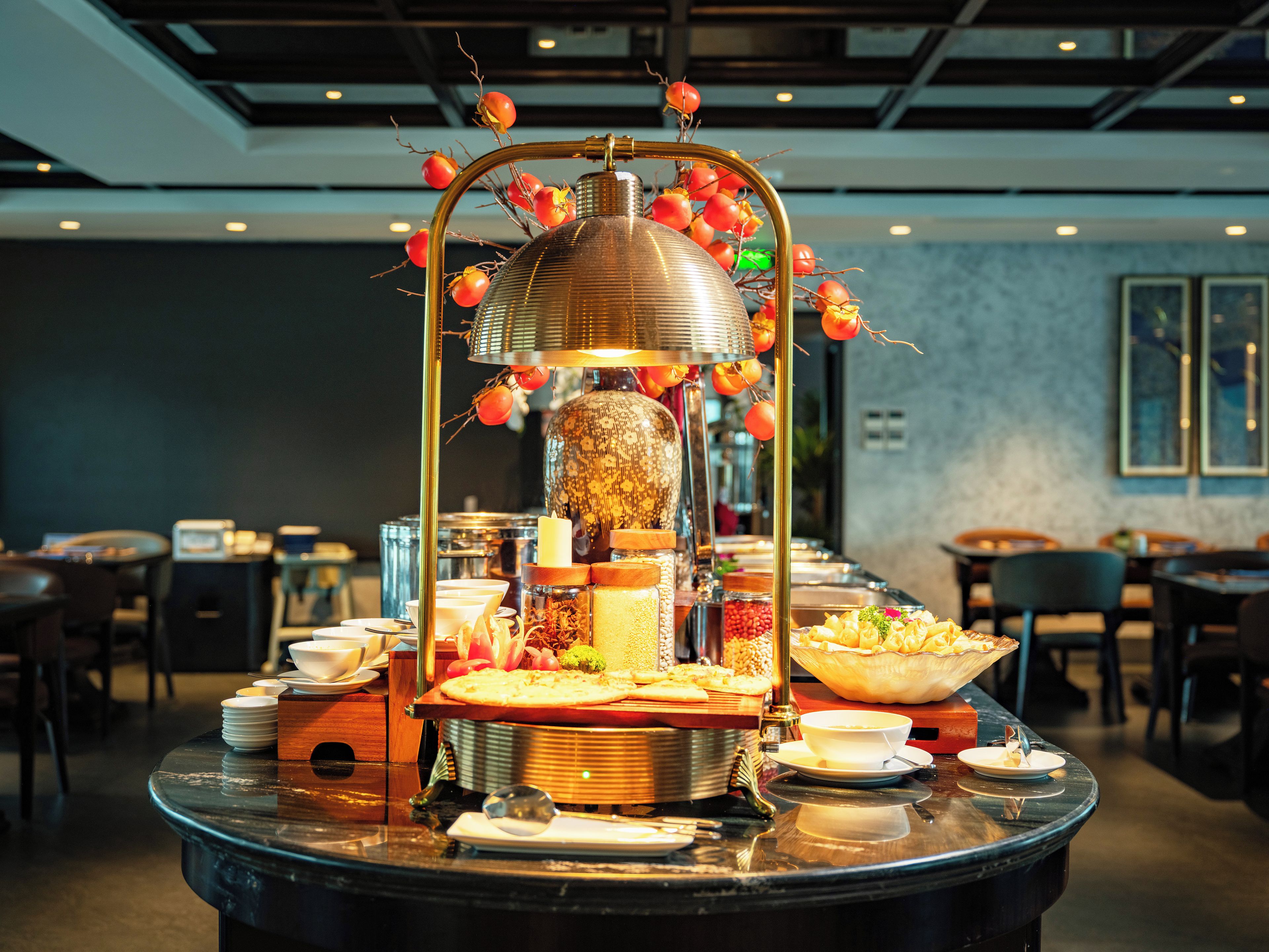 A buffet setup with a central decorative piece, surrounded by various food items and serving dishes.