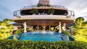 A hotel with a pool, outdoor seating, and a statue in the foreground. - Celina of The Sea Cruise (Tuan Chau)