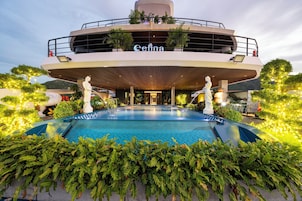 Un hotel con piscina, mobiliario exterior y una estatua al frente.