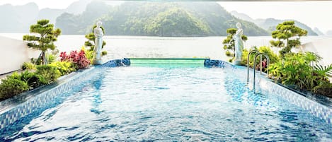 An indoor swimming pool with a view of a lake and mountains.