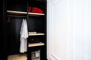 Une armoire noire avec plusieurs étagères, une tringle et un petit réfrigérateur.