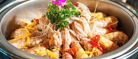 A large metal pot filled with cooked shrimp garnished with parsley and lemon slices.
