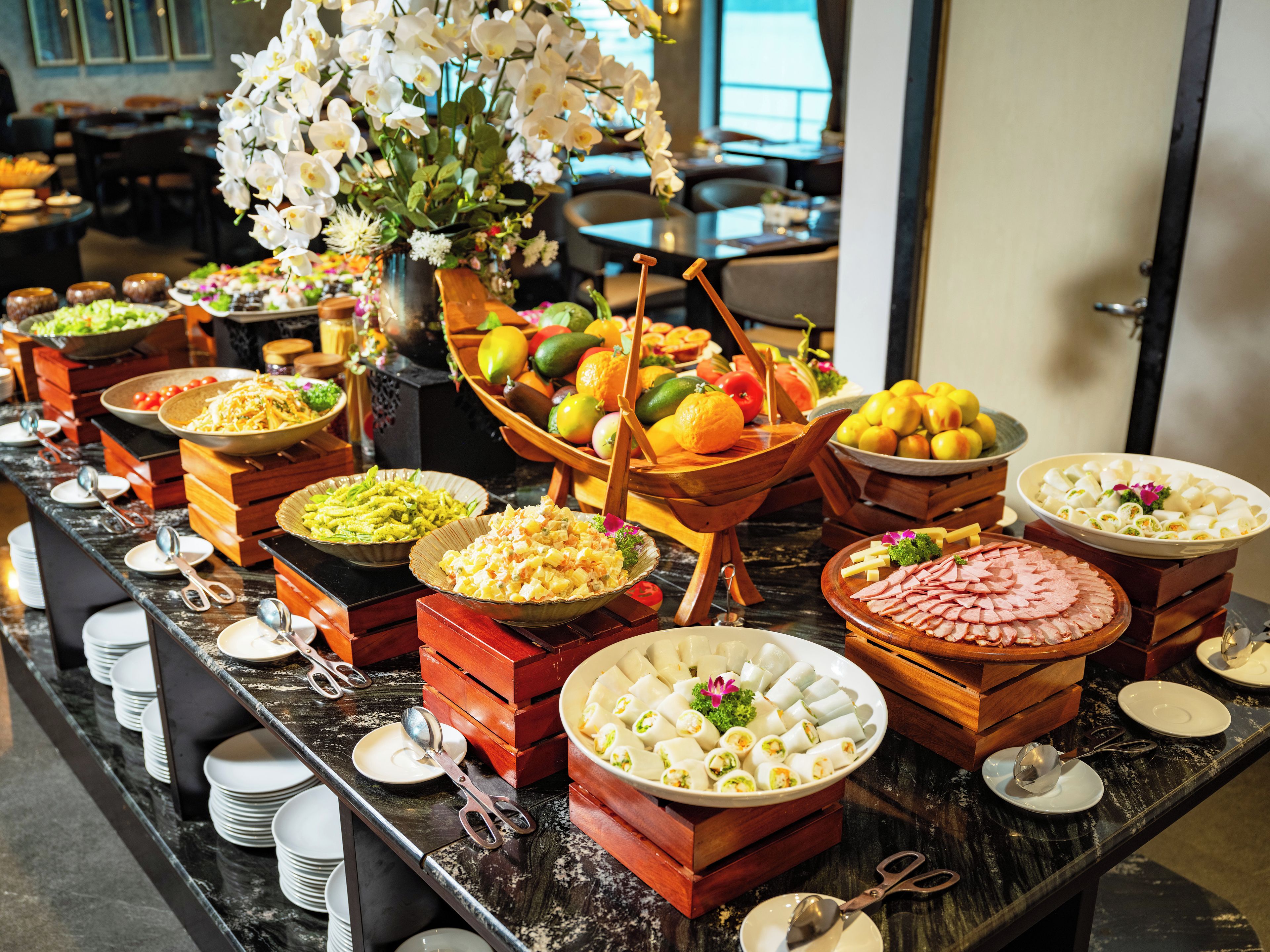 A buffet with various food items and a decorative flower arrangement.