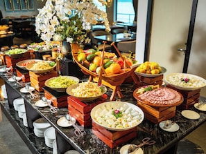 A buffet with various food items and a decorative flower arrangement. - Celina of The Sea Cruise (Tuan Chau)