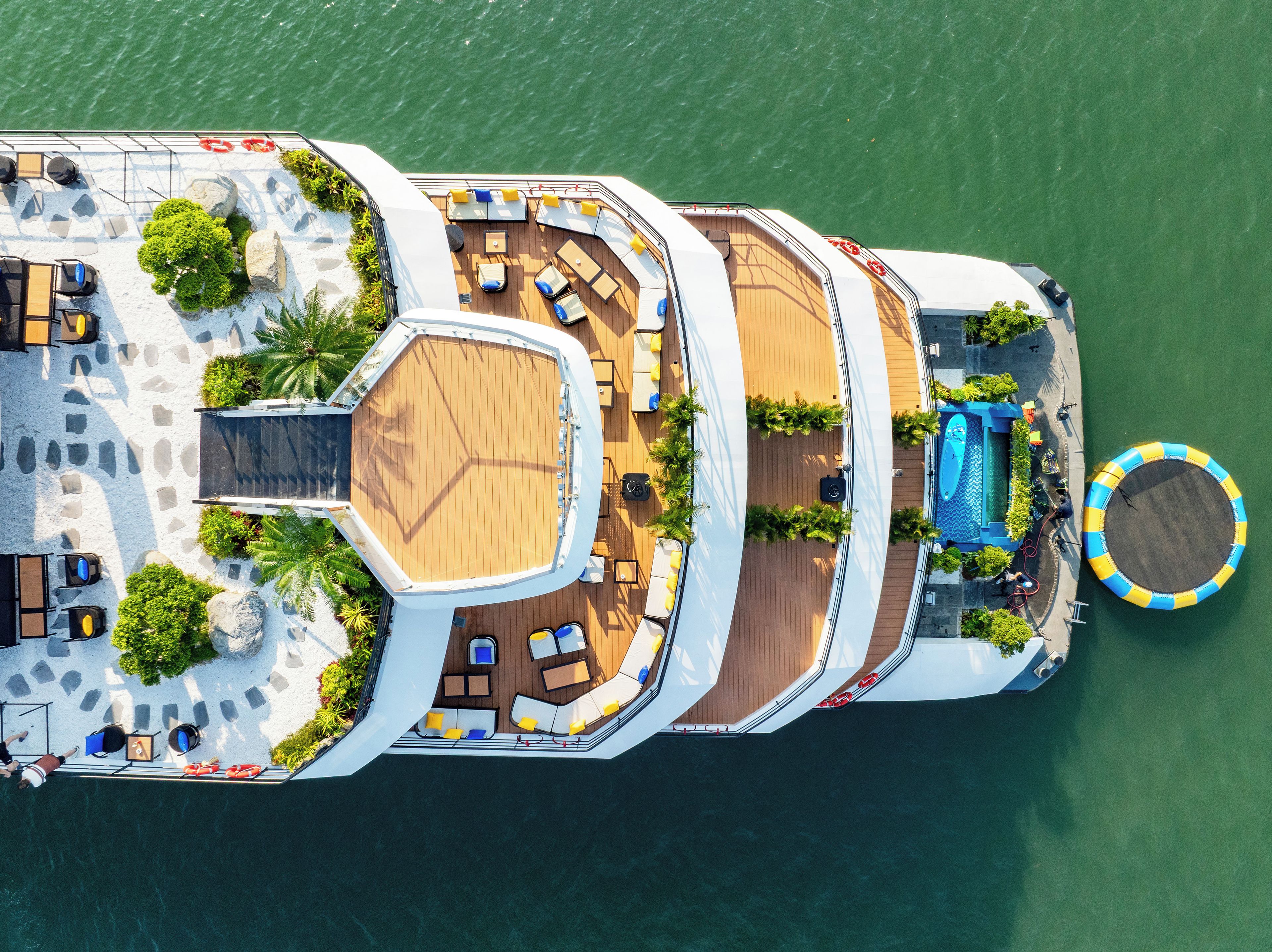 An aerial view of a cruise ship deck with multiple sun loungers, a swimming pool, and a lifebuoy.