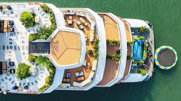 An aerial view of a cruise ship deck with multiple sun loungers, a swimming pool, and a lifebuoy.