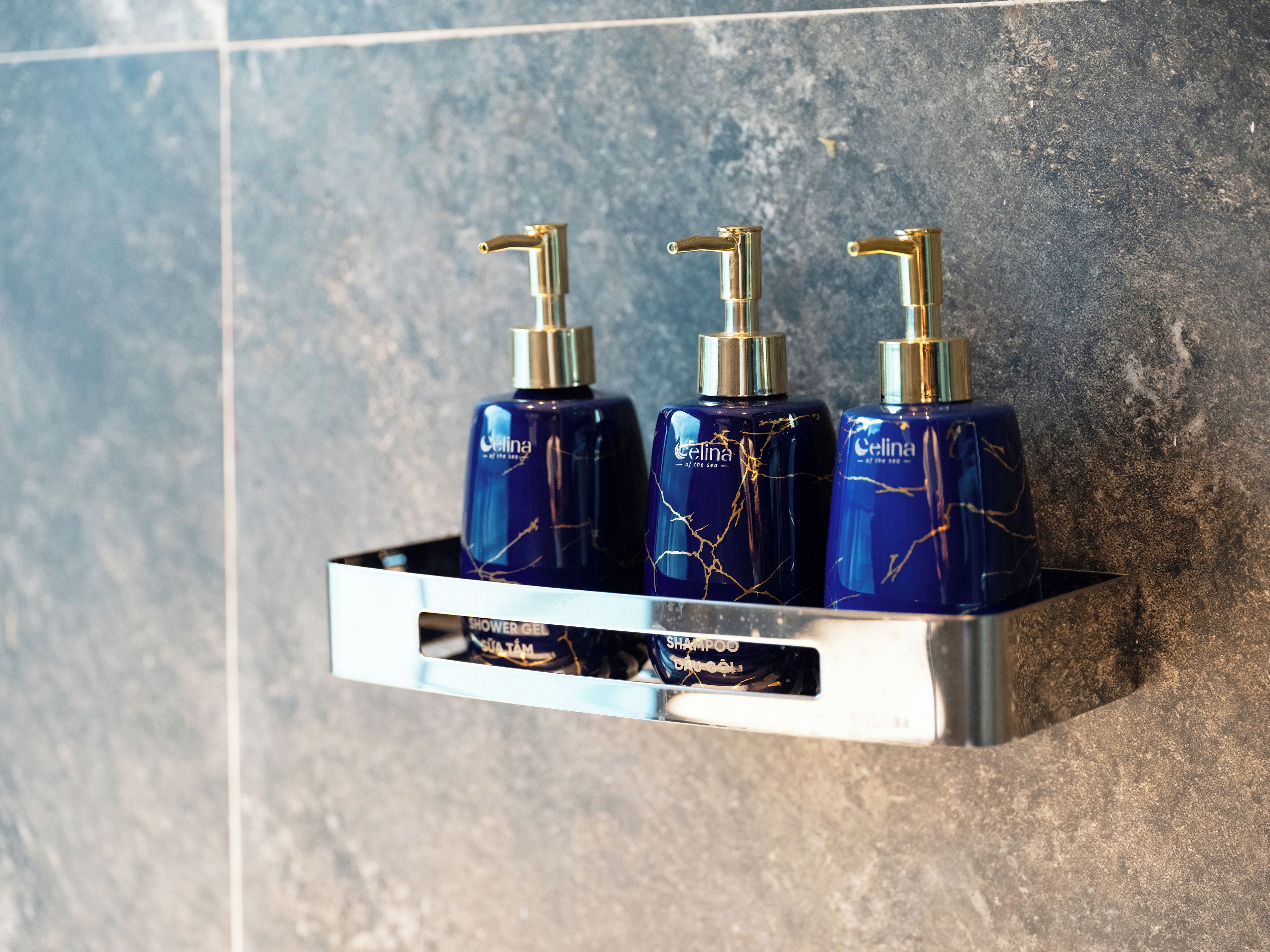 A bathroom shelf with three bottles of Celina shower gel and shampoo.