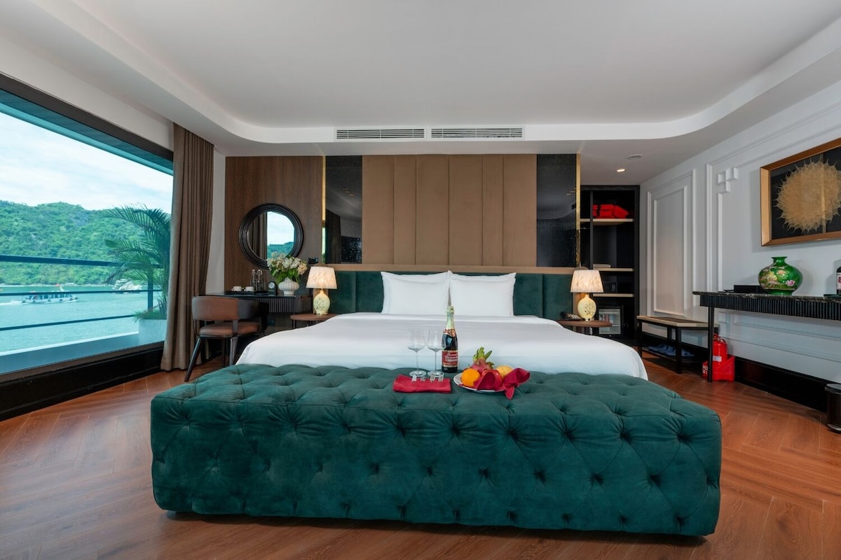 Une chambre spacieuse avec un grand lit, un bureau et une vue sur la mer.