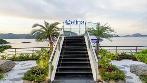 A staircase leading to a building with the name 'Celina' on top, surrounded by greenery and overlooking a body of water. - Celina of The Sea Cruise (Tuan Chau)