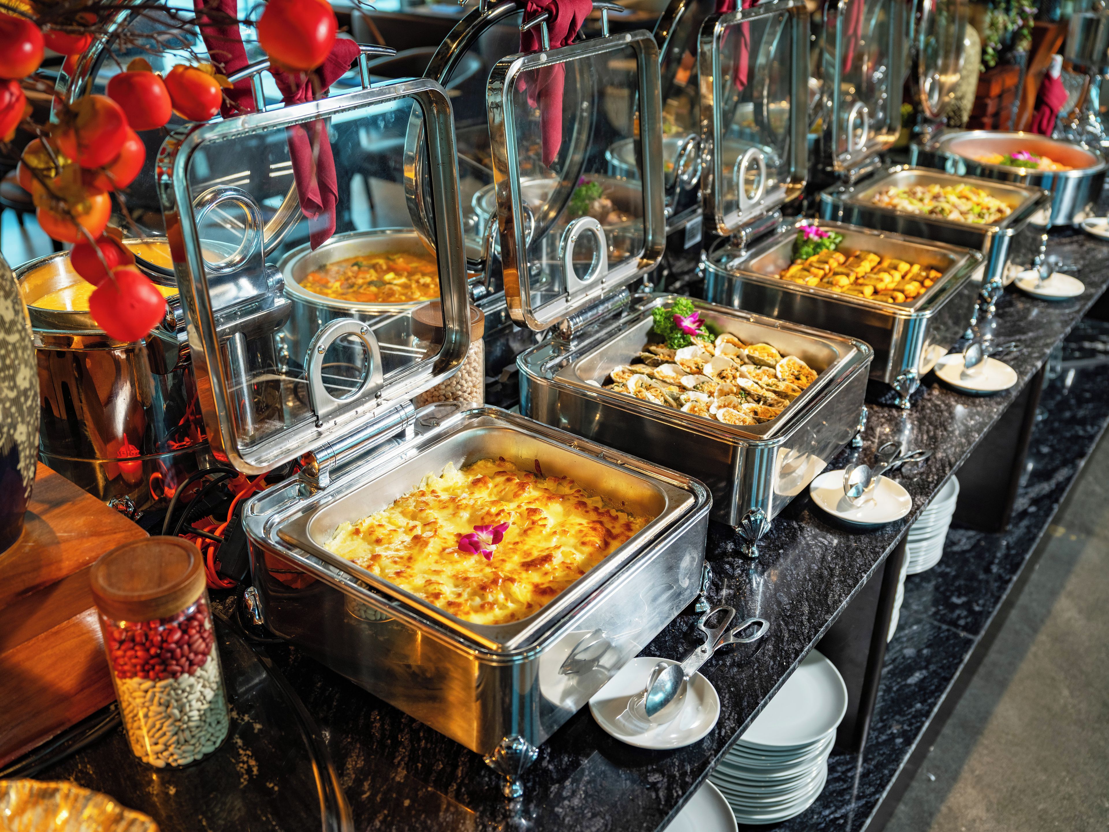 A buffet with various food options, including a casserole dish, covered with a glass dome.