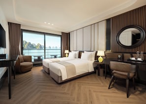 A hotel room with a bed, two bedside tables, a desk, a chair, a TV, and a large window offering a view of the sea. - Celina of The Sea Cruise (Tuan Chau)