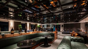 Un espace lounge moderne avec des fauteuils en cuir, des tables en bois et un bar.