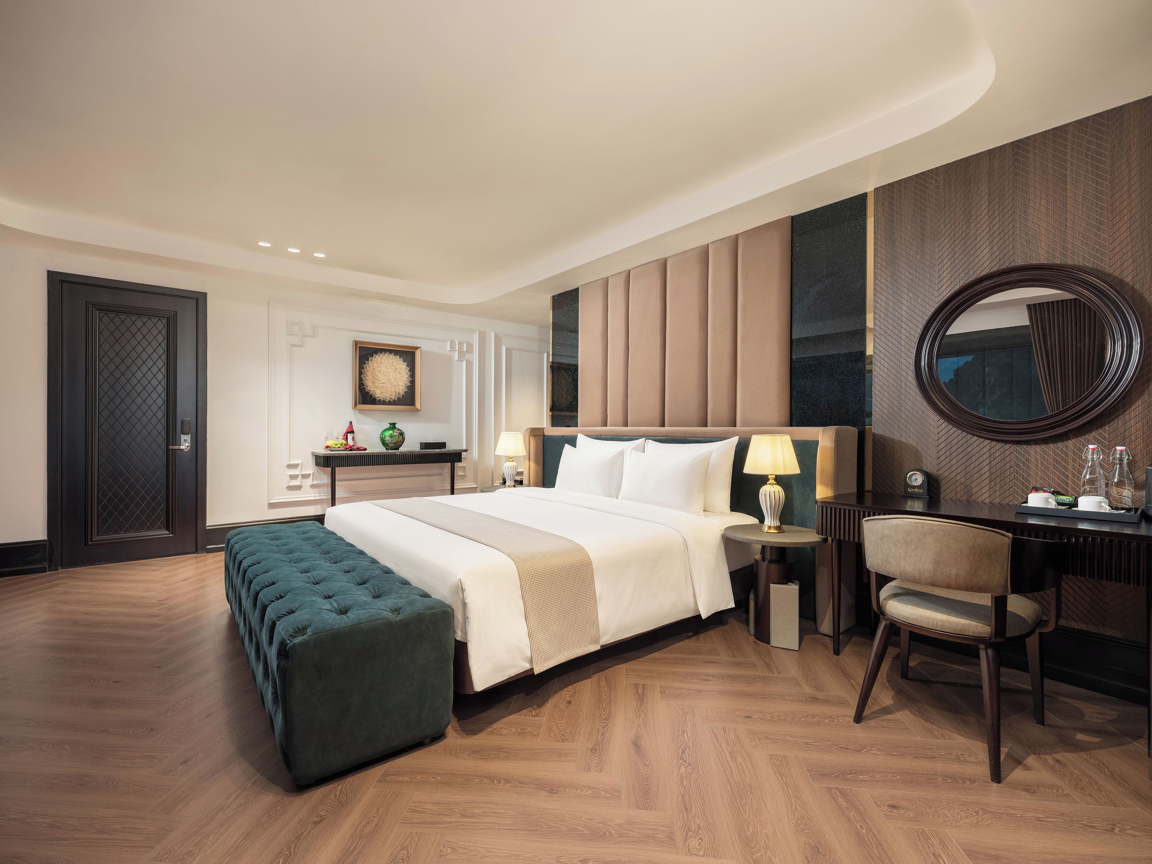 Una habitación de hotel con una cama grande, un escritorio con silla, un espejo redondo y suelo de madera.