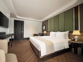 A hotel room with a large bed, a desk, a television, and a mirror.