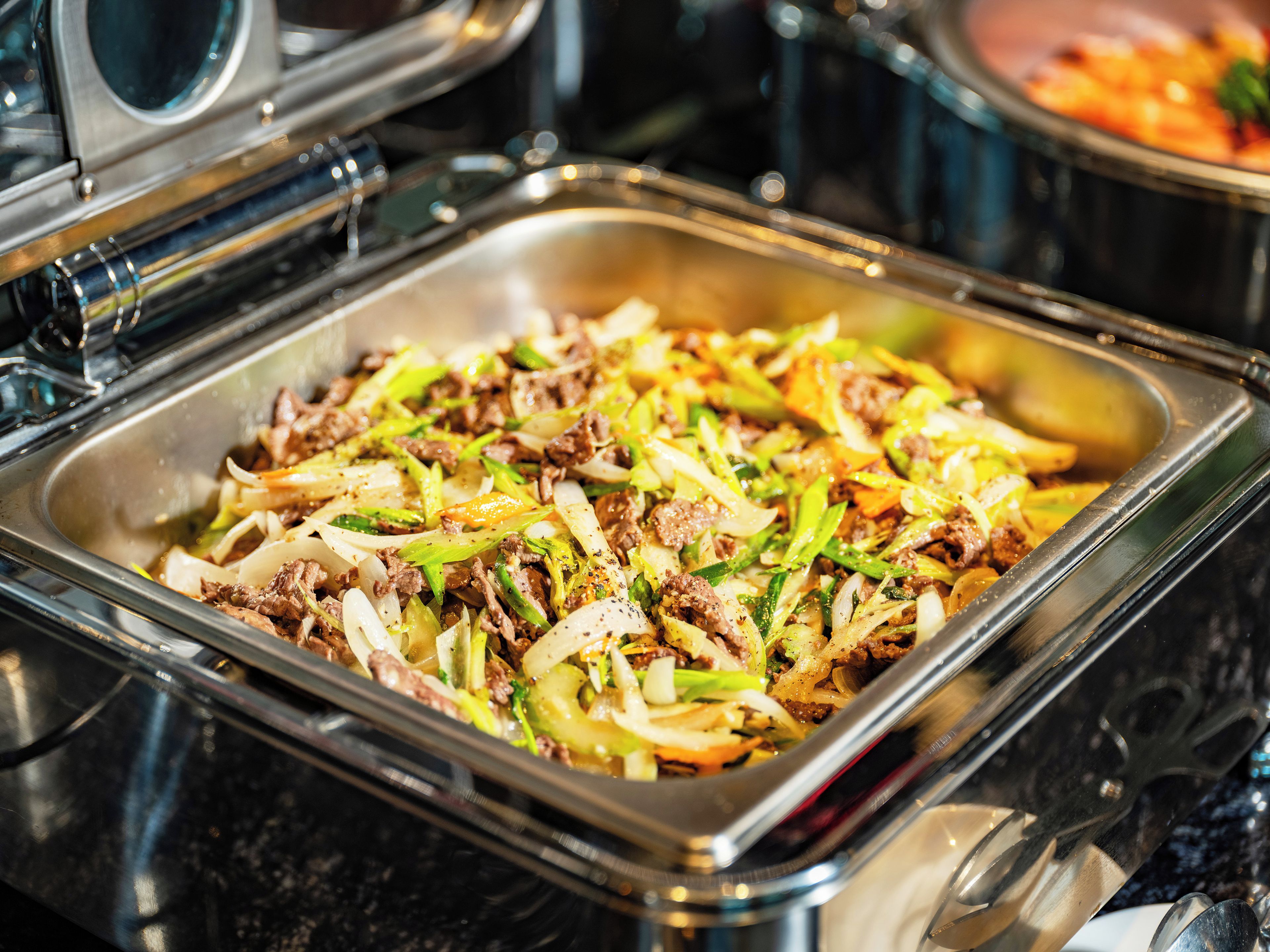 A buffet with a variety of dishes including meat and vegetables.