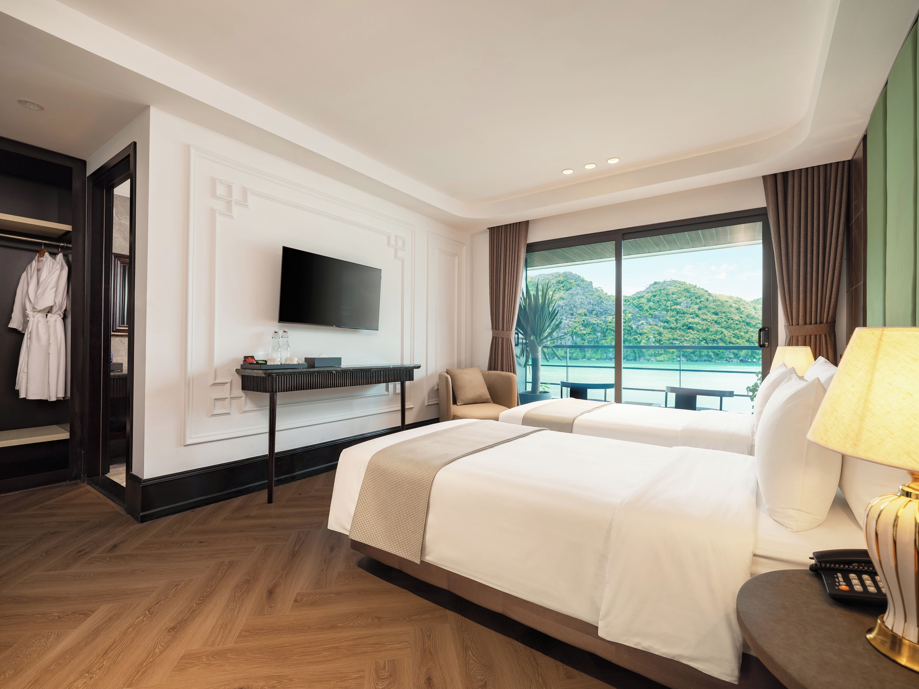 A hotel room with a large bed, a TV, a desk, and a view of a body of water.