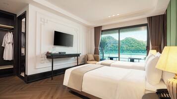 A hotel room with a large bed, a TV, a desk, and a view of a body of water.