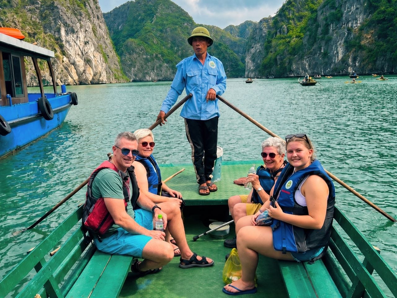 A group of people on a boat with a guide, surrounded by water and cliffs.