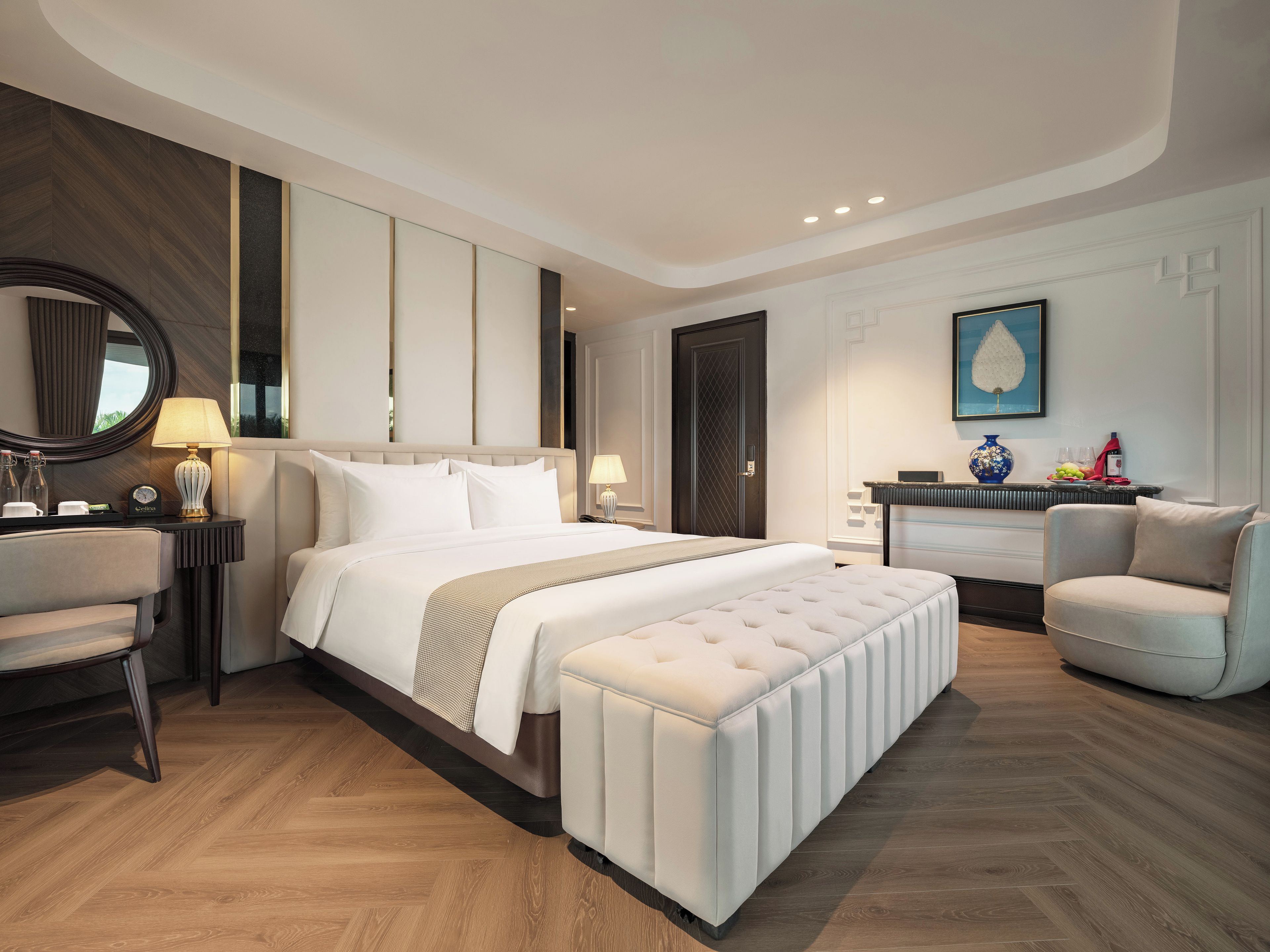 Una habitación de hotel moderna con una cama grande, una zona de estar con una silla, un escritorio y una tocador con espejo.