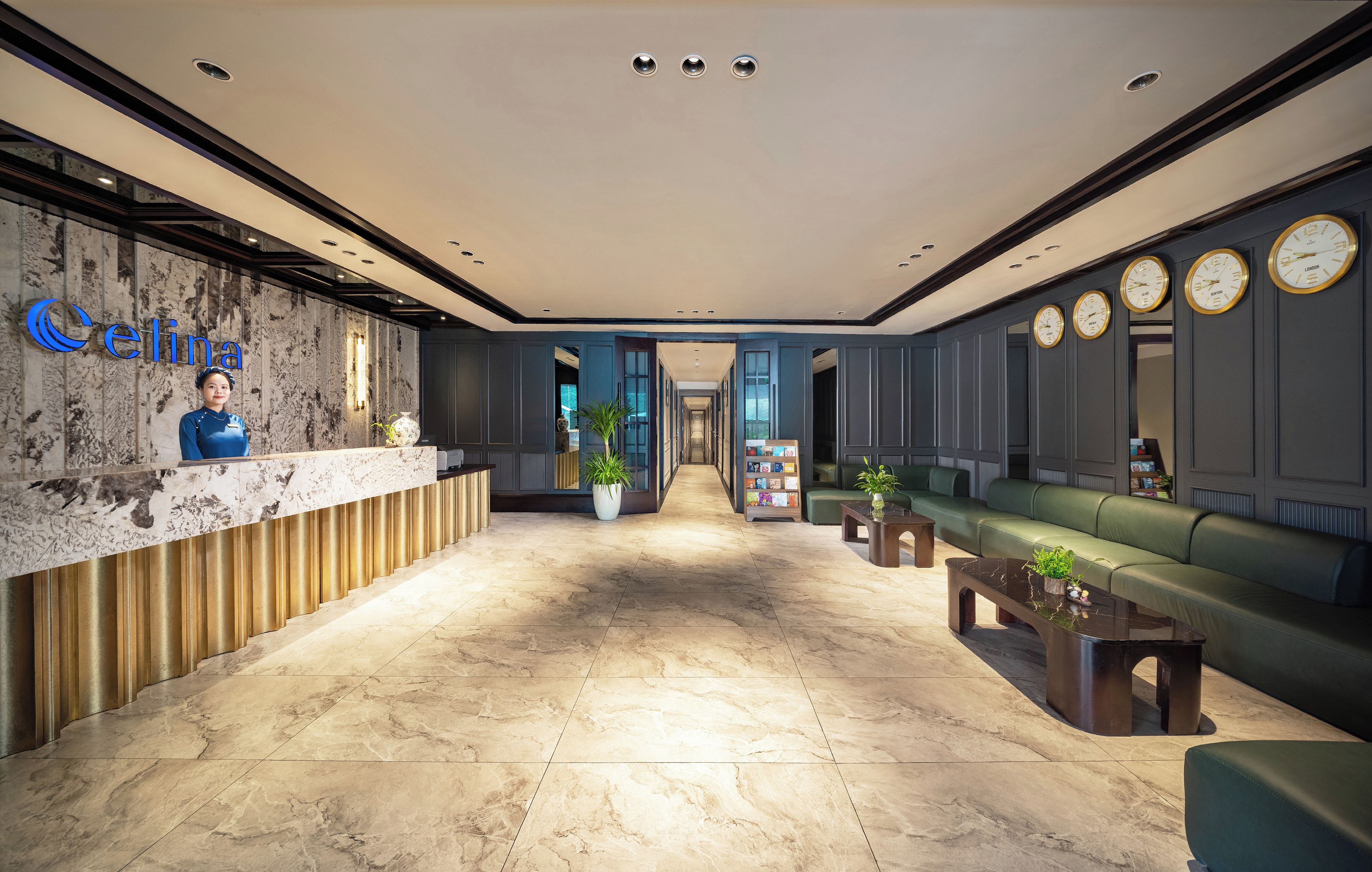 A hotel reception area with a marble floor, a reception desk, a green sofa, and wall clocks.