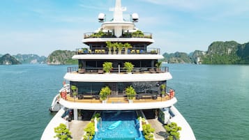 A multi-level yacht with a swimming pool, outdoor seating, and a helipad.