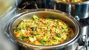 Un buffet proposant divers plats, notamment un sauté de légumes et un plat à base de nouilles.