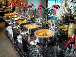 Montaje de bufé con varios recipientes de comida y utensilios.